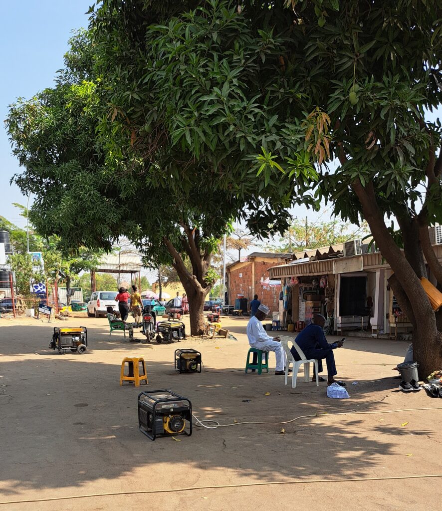 When grid power fails at Abuja’s Wuse Market, most shops fire up fossil-fueled generators, spiking noise levels and air pollution.