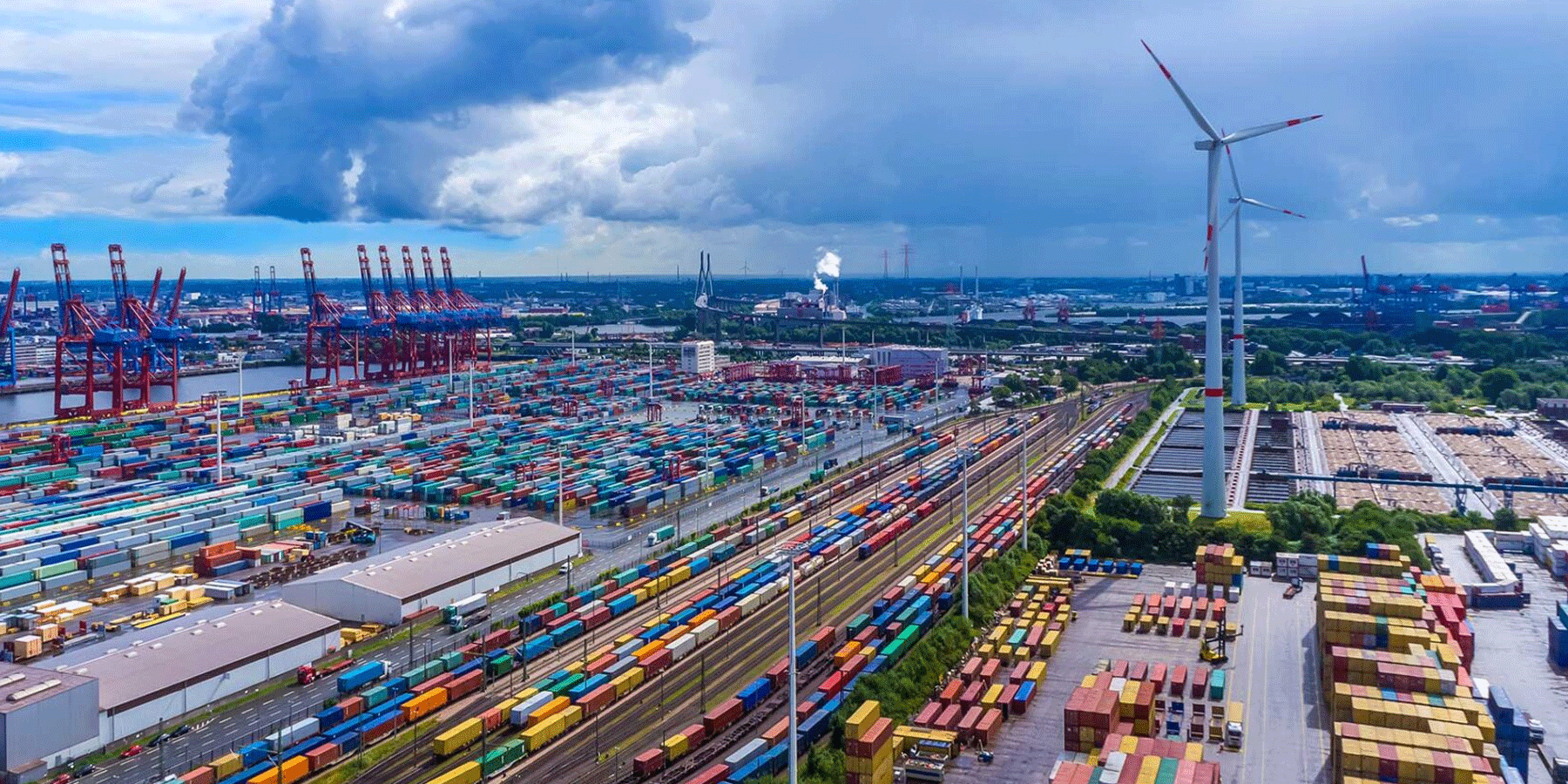 aerial view of a port with shipping containers and wind turbines