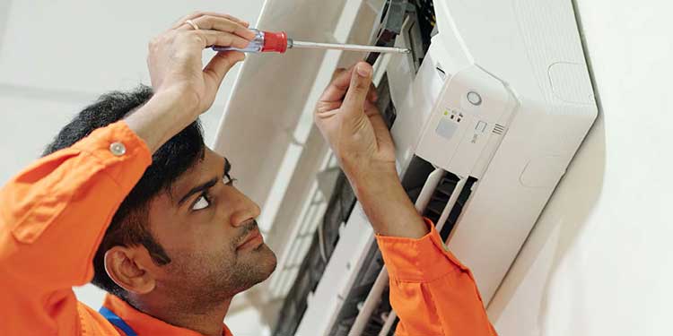 man adjusting air conditioner with screwdriver