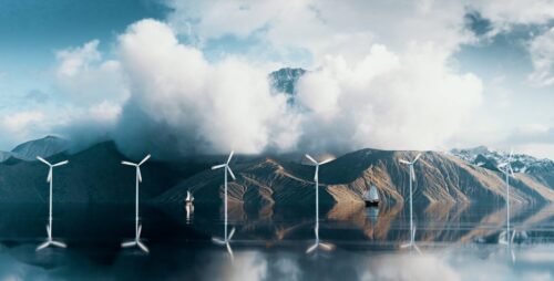 coastal wind farm with mountains and clouds in background