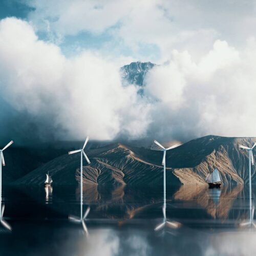 coastal wind farm with mountains and clouds in background