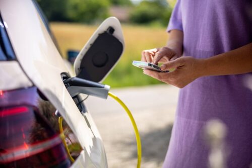 woman on phone in front of ev charger