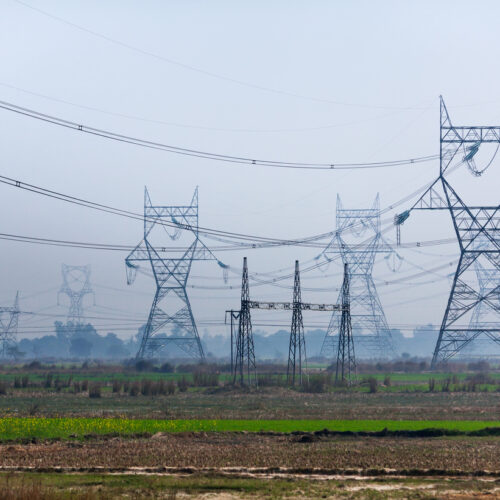 Transmission towers of lines of high voltage standing on the Indian plain.