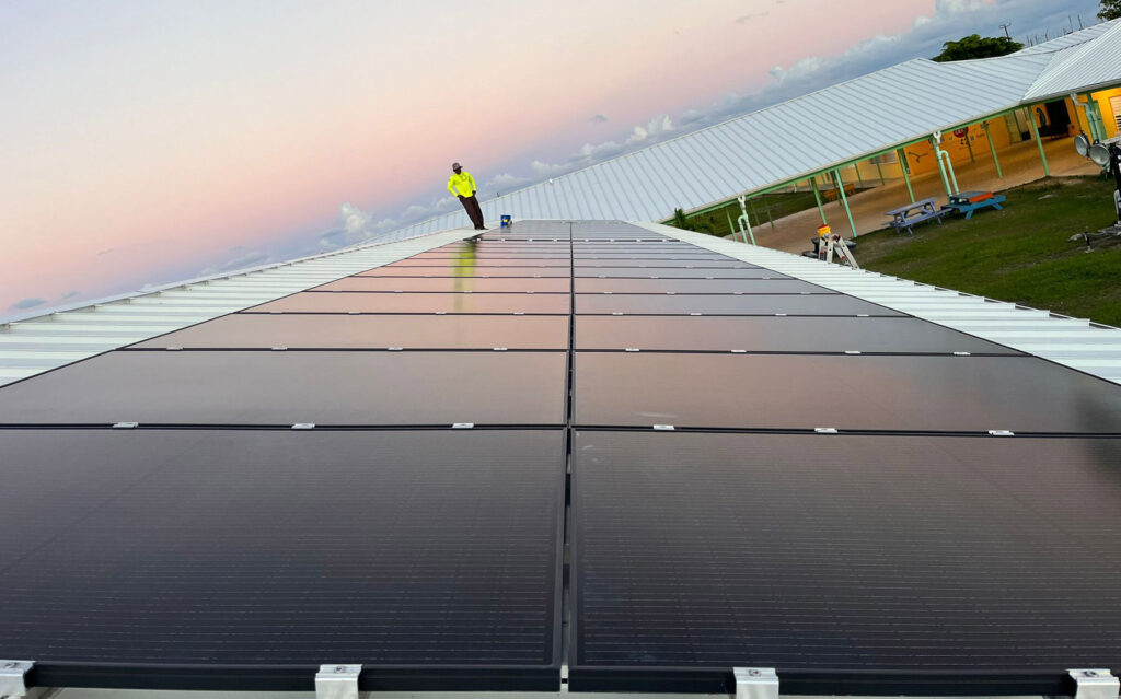 Compass Solar installer at sunrise on the roof of Abaco Central Primary completing the solar installations. Photo credit Compass Solar.