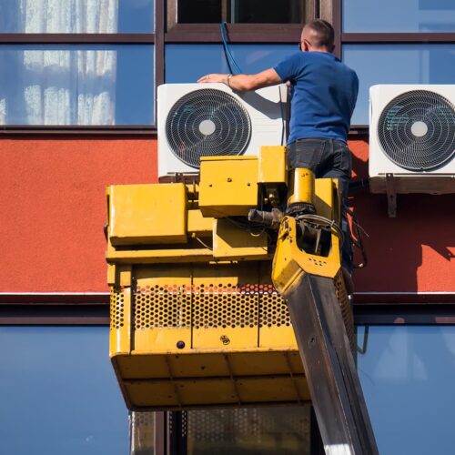 man installing ac unit on building