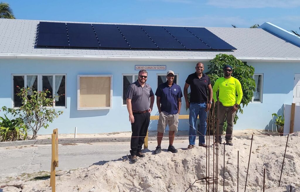 The RMI and Compass Solar Team smile in front of the completed solar and storage installation at Great Guana Cay Primary School. Photo credit RMI.