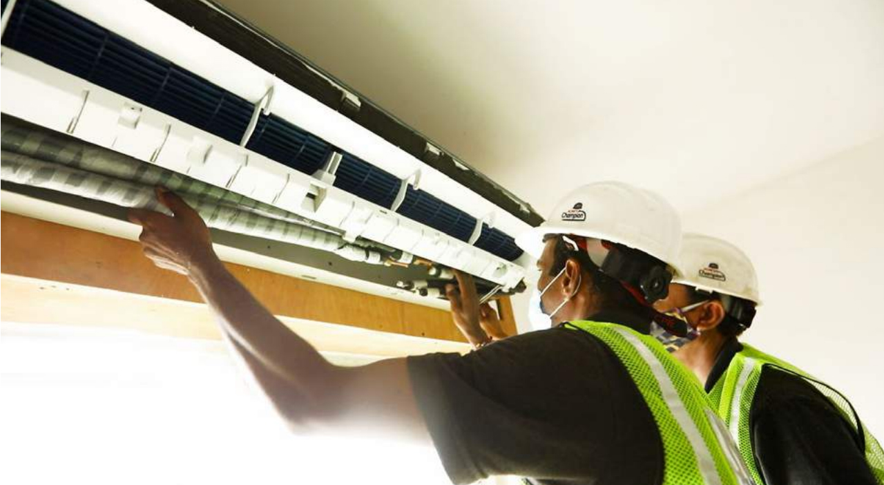 Two workers installing an air con system