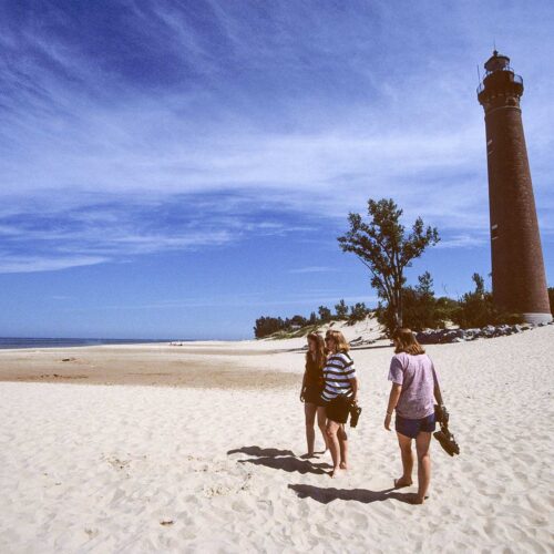 beach with lighthouse and people walking