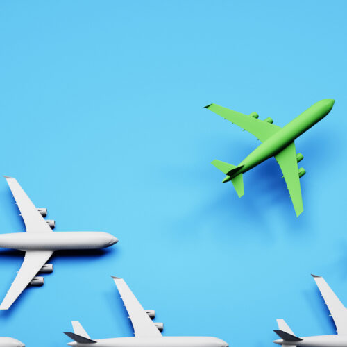 Group of white airplanes with green leader on blue background - green energy travel concept