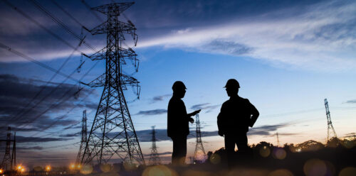two technicians by a powerline at twilight