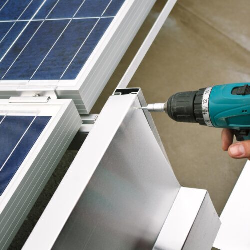 man drilling solar panels for installation