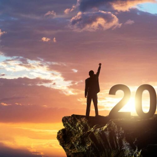 Businessman standing on the top of rock with number 2024