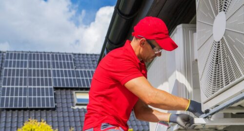 HVAC Worker Performing Heat Pump Maintenance. Device is Transferring Thermal Energy From the Outside Using the Refrigeration Cycle. Home Heating Technologies.