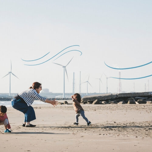 family on the beach with wind turbines in the background